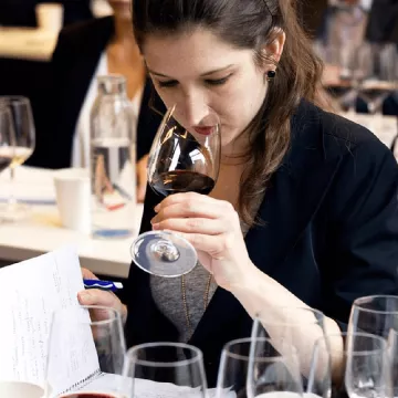 A woman smells a glass of red wine